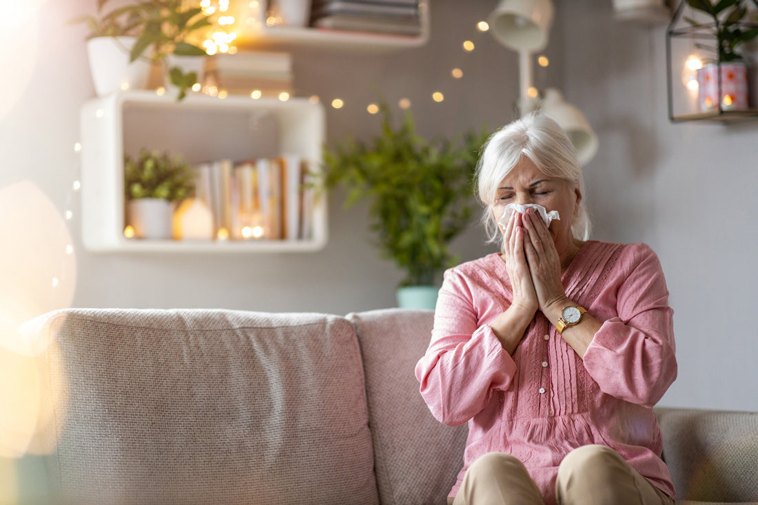 Woman Sneezing in Tissue sitting on couch in living room